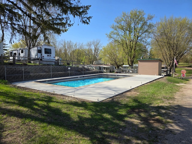 view of swimming pool featuring a yard, fence, a fenced in pool, and an outdoor structure