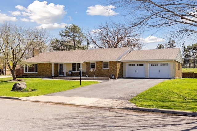 ranch-style home featuring a garage, a chimney, aphalt driveway, and brick siding