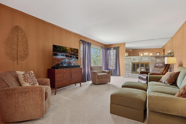 living room featuring carpet flooring, wood walls, and a stone fireplace
