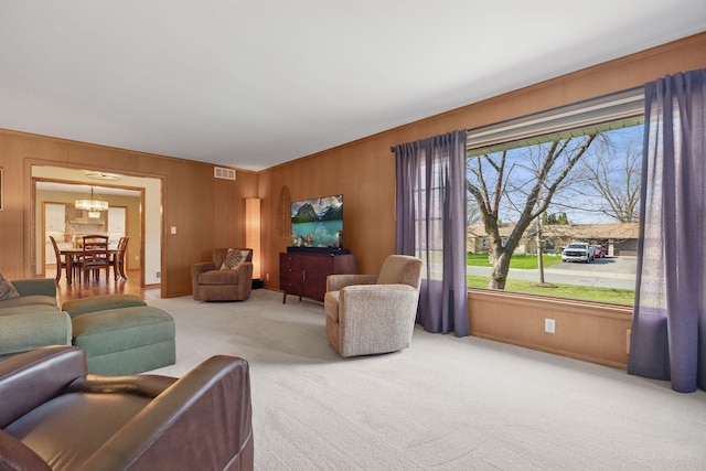 living area featuring carpet floors, wooden walls, and visible vents