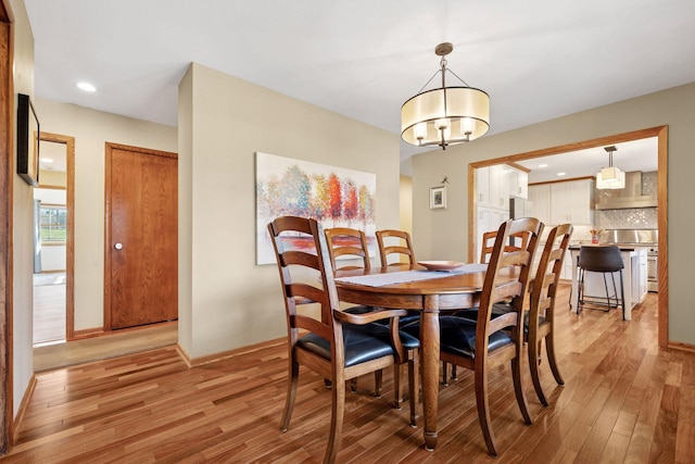 dining space with light wood-style floors, baseboards, an inviting chandelier, and recessed lighting