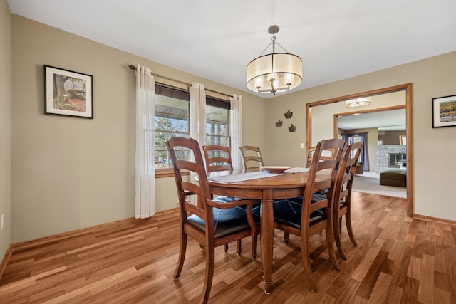 dining room with an inviting chandelier, baseboards, and light wood finished floors