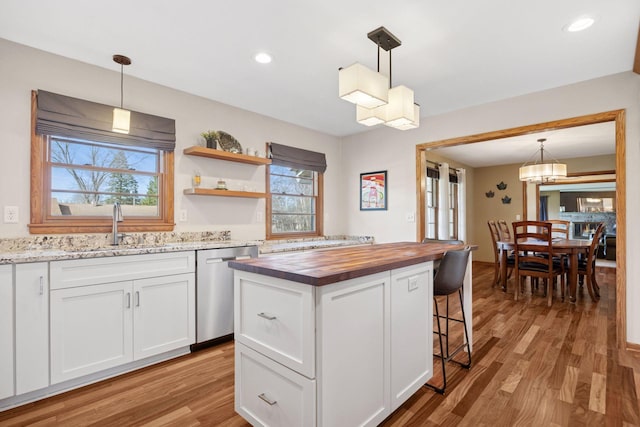 kitchen featuring white cabinets, a sink, plenty of natural light, stainless steel dishwasher, and butcher block counters