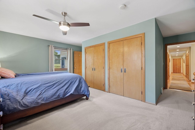 bedroom with multiple closets, light carpet, and a ceiling fan