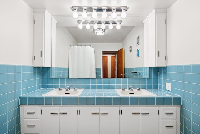 bathroom featuring a sink, tile walls, and double vanity
