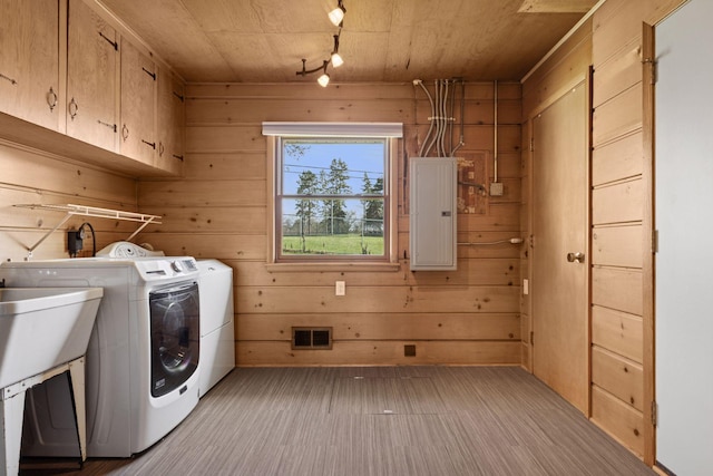 washroom with cabinet space, wooden walls, washing machine and clothes dryer, visible vents, and electric panel