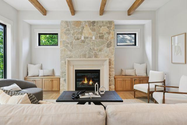 9399 Eagle Ridge Way, Chanhassen, MN 55317 - living room featuring light wood-style flooring, a stone fireplace, and beamed ceiling