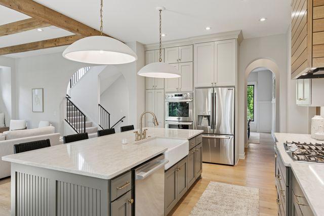 9399 Eagle Ridge Way, Chanhassen, MN 55317 - kitchen with appliances with stainless steel finishes, gray cabinetry, arched walkways, light wood-style floors, and hanging light fixtures