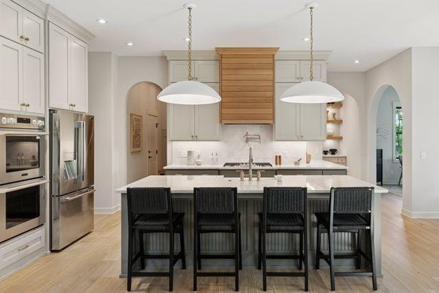 9399 Eagle Ridge Way, Chanhassen, MN 55317 - kitchen featuring appliances with stainless steel finishes, arched walkways, light countertops, backsplash, and recessed lighting