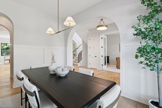 9399 Eagle Ridge Way, Chanhassen, MN 55317 - dining room featuring arched walkways, light wood-type flooring, stairway, and wainscoting