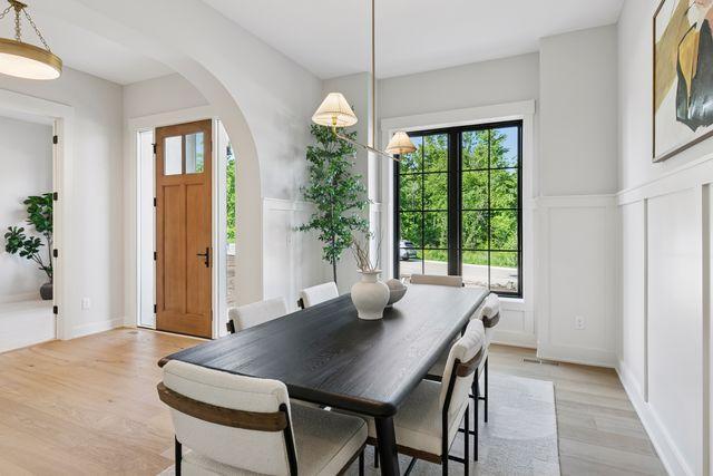 9399 Eagle Ridge Way, Chanhassen, MN 55317 - dining area with a decorative wall, light wood-style floors, plenty of natural light, arched walkways, and a wainscoted wall