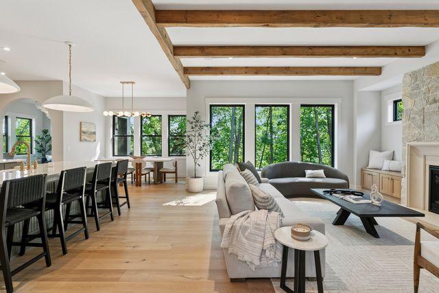 9399 Eagle Ridge Way, Chanhassen, MN 55317 - living area featuring light wood-style floors, beam ceiling, a fireplace, and a chandelier