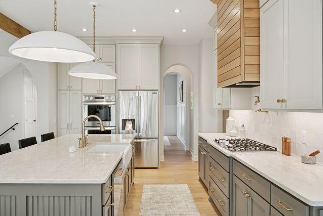 9399 Eagle Ridge Way, Chanhassen, MN 55317 - kitchen with stainless steel appliances, gray cabinets, arched walkways, light wood finished floors, and recessed lighting