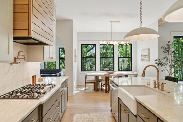 9399 Eagle Ridge Way, Chanhassen, MN 55317 - kitchen featuring stainless steel appliances, premium range hood, decorative backsplash, decorative light fixtures, and light wood-style flooring