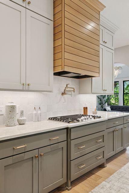 9399 Eagle Ridge Way, Chanhassen, MN 55317 - kitchen with gray cabinets, range hood, stainless steel gas cooktop, and decorative backsplash