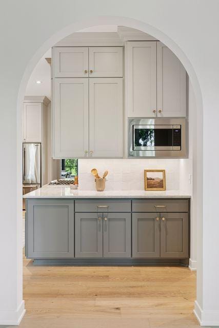 9399 Eagle Ridge Way, Chanhassen, MN 55317 - kitchen with stainless steel microwave, gray cabinetry, light wood-style flooring, and light countertops