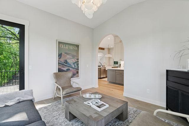 9399 Eagle Ridge Way, Chanhassen, MN 55317 - living area featuring a chandelier, vaulted ceiling, light wood-style flooring, and arched walkways