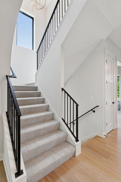 9399 Eagle Ridge Way, Chanhassen, MN 55317 - staircase with wood finished floors, a chandelier, and arched walkways