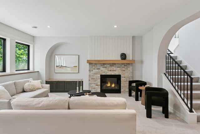 9399 Eagle Ridge Way, Chanhassen, MN 55317 - living area featuring carpet flooring, stairs, a brick fireplace, arched walkways, and recessed lighting
