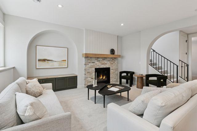 9399 Eagle Ridge Way, Chanhassen, MN 55317 - living area with arched walkways, light carpet, stairs, recessed lighting, and a fireplace