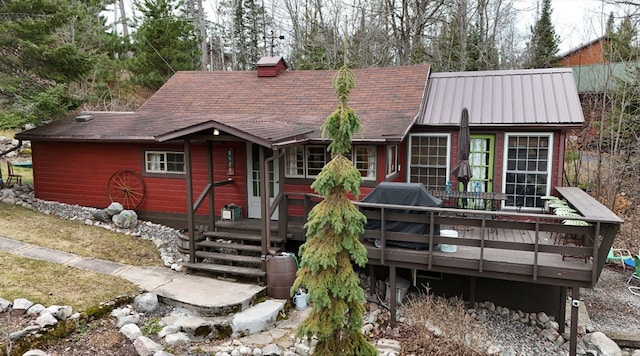 rear view of house featuring a shingled roof, a wooden deck, and a chimney