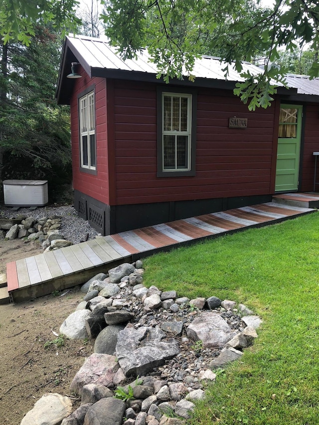 exterior space featuring a lawn, a standing seam roof, an outbuilding, and metal roof