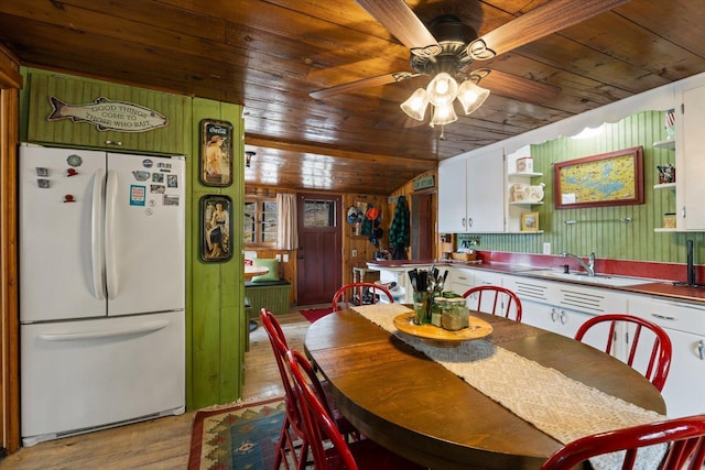 dining space featuring wooden walls, wooden ceiling, a ceiling fan, and light wood-type flooring