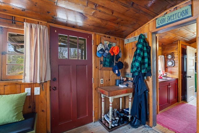 foyer entrance with a wealth of natural light, lofted ceiling, wooden walls, and wooden ceiling