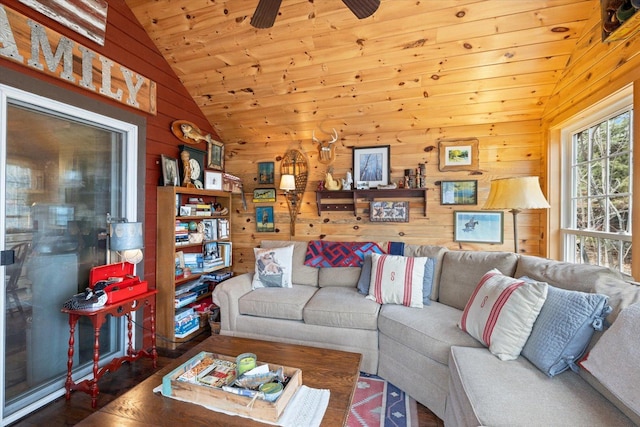 living area with wood finished floors, lofted ceiling, ceiling fan, wooden walls, and wood ceiling