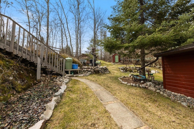 view of yard with an outdoor structure, stairs, and a storage unit