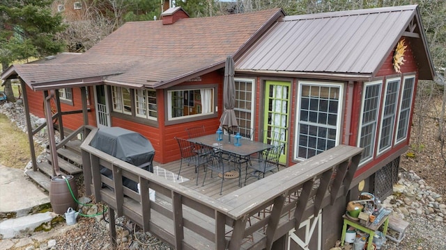back of property featuring a wooden deck, metal roof, a chimney, and outdoor dining space