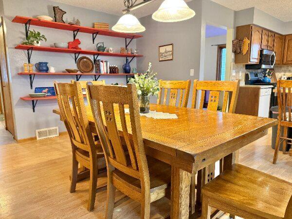 dining room with light wood finished floors, visible vents, and baseboards