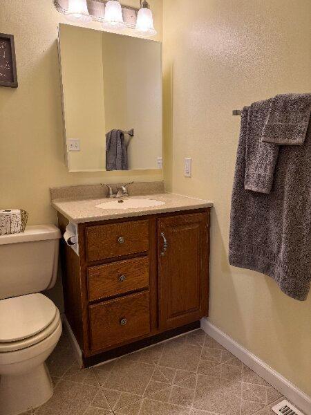 bathroom featuring toilet, baseboards, vanity, and visible vents