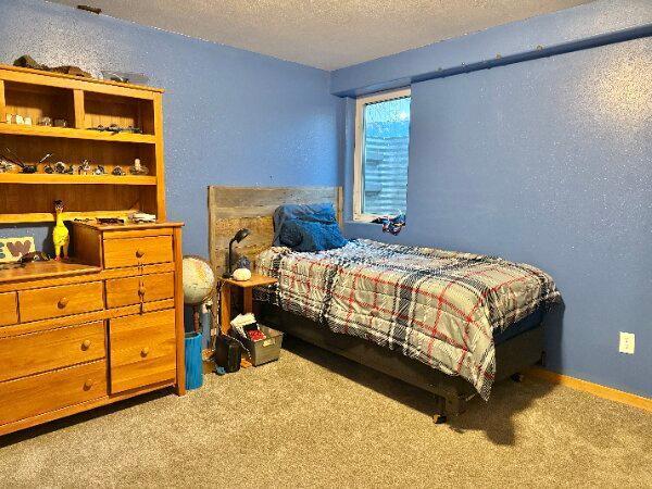 carpeted bedroom featuring a textured ceiling and a textured wall