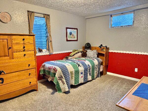 carpeted bedroom with a textured ceiling and a textured wall
