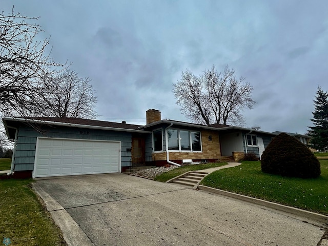 view of front facade with a chimney, an attached garage, driveway, and a front lawn