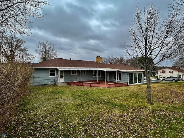 rear view of house with a wooden deck, a yard, and a chimney