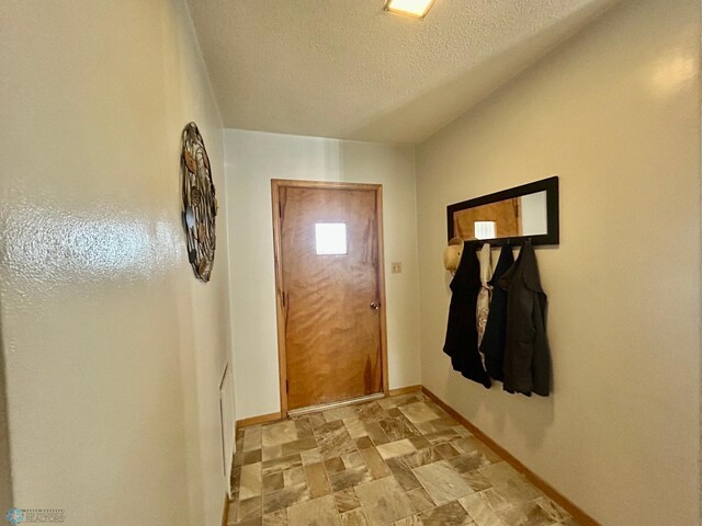 entryway with baseboards, a textured ceiling, and stone finish floor