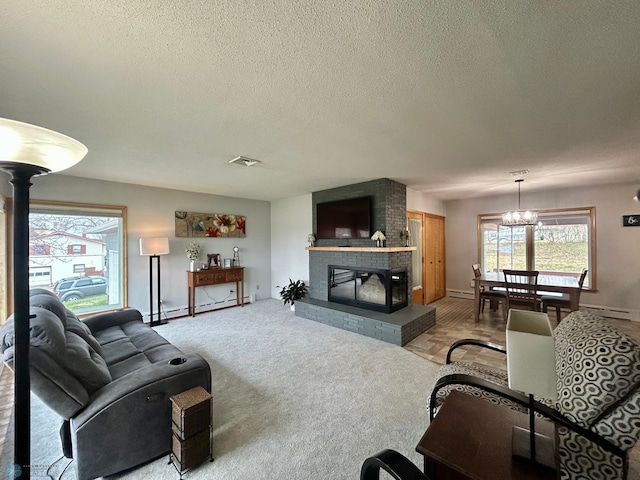 living area with a textured ceiling, visible vents, a fireplace, baseboard heating, and a baseboard heating unit