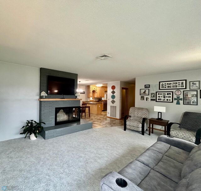 living area with carpet floors, a textured ceiling, visible vents, and a fireplace