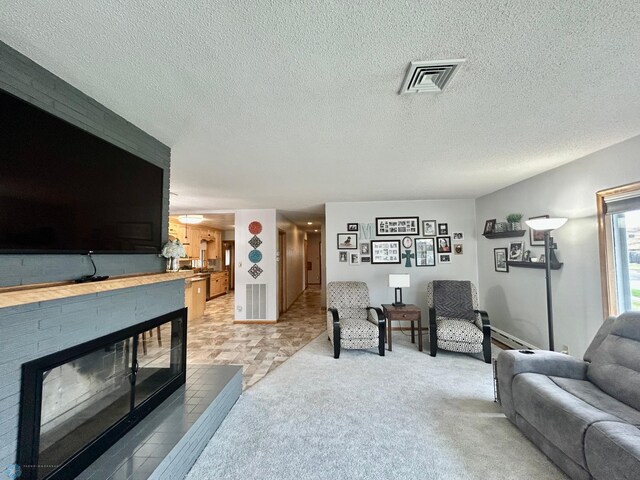 living room featuring visible vents, a baseboard radiator, a textured ceiling, and a fireplace