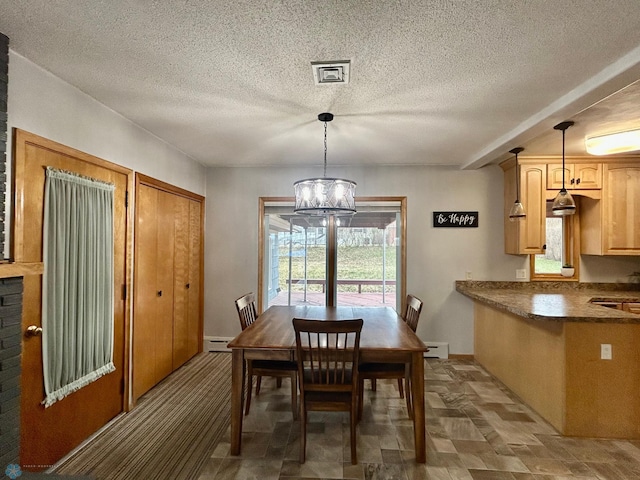 dining area featuring a notable chandelier, baseboard heating, a textured ceiling, stone finish floor, and a baseboard heating unit