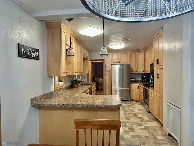 kitchen with visible vents, a peninsula, dark countertops, a sink, and stainless steel appliances