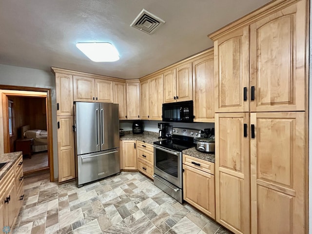 kitchen featuring stainless steel appliances, visible vents, stone finish floor, and light brown cabinets
