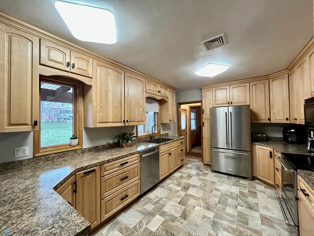kitchen with a sink, light brown cabinets, stainless steel appliances, and visible vents