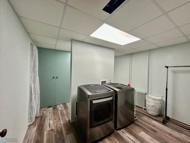 washroom featuring laundry area, radiator, wood finished floors, and washer and dryer
