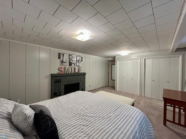 bedroom with carpet flooring, a brick fireplace, a decorative wall, and two closets