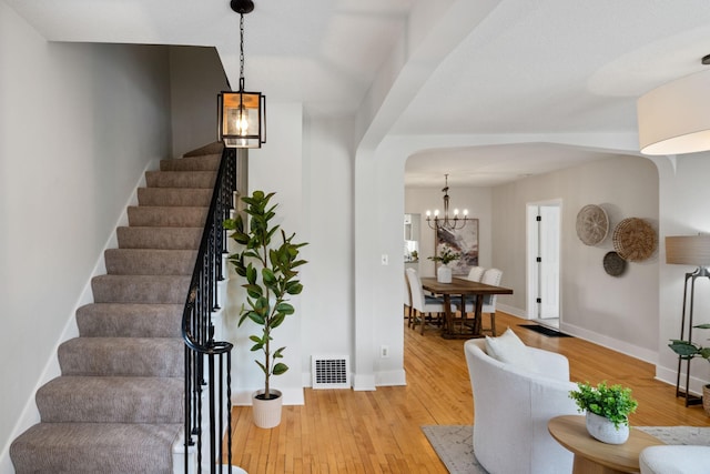 foyer entrance with stairs, arched walkways, visible vents, and hardwood / wood-style floors