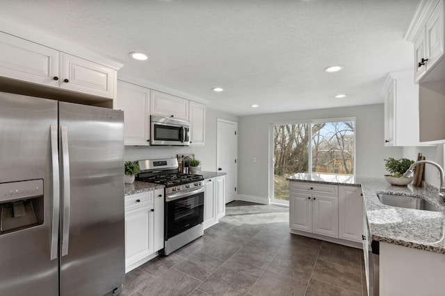 kitchen featuring a sink, stainless steel appliances, recessed lighting, white cabinetry, and a peninsula