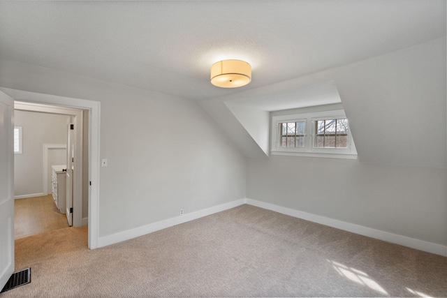 bonus room with baseboards, visible vents, and carpet